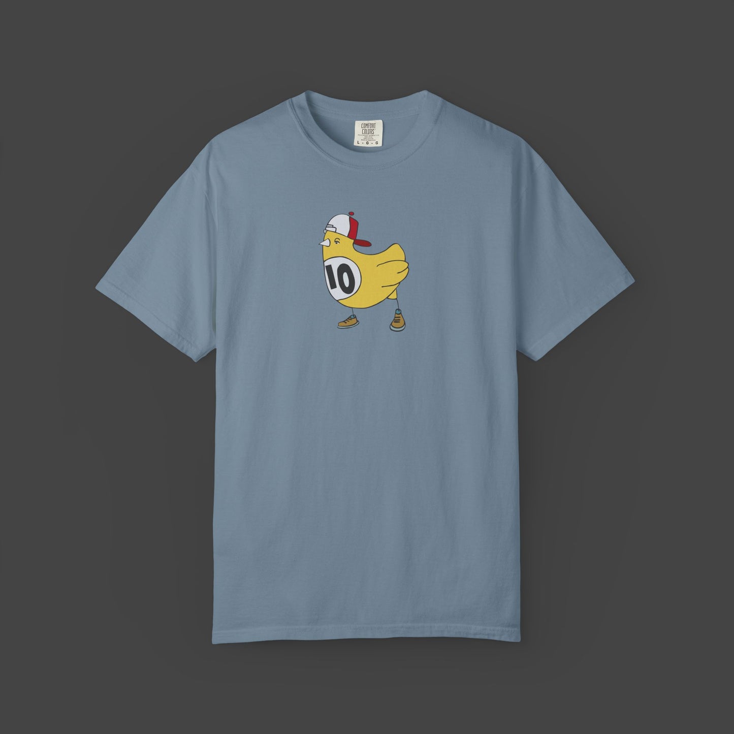 The Chicken Scratch Unisex T-shirt by Jarrod Eastman from Printify features a cartoon yellow bird in a red-and-white cap, brown shoes, and a #10 bib—delivering a surreal, fun design on this garment-dyed tee.