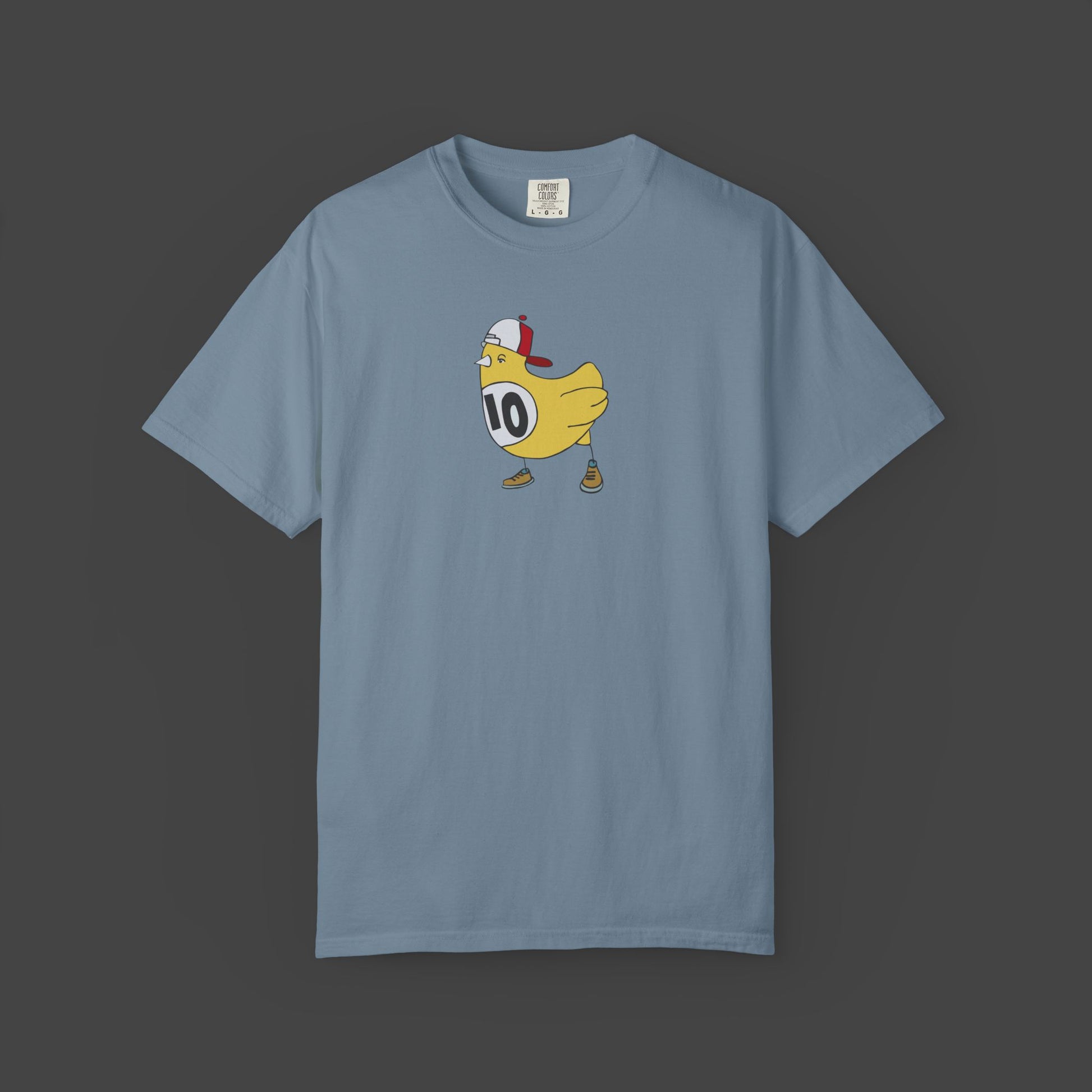 The Chicken Scratch Unisex T-shirt by Jarrod Eastman from Printify features a cartoon yellow bird in a red-and-white cap, brown shoes, and a #10 bib—delivering a surreal, fun design on this garment-dyed tee.