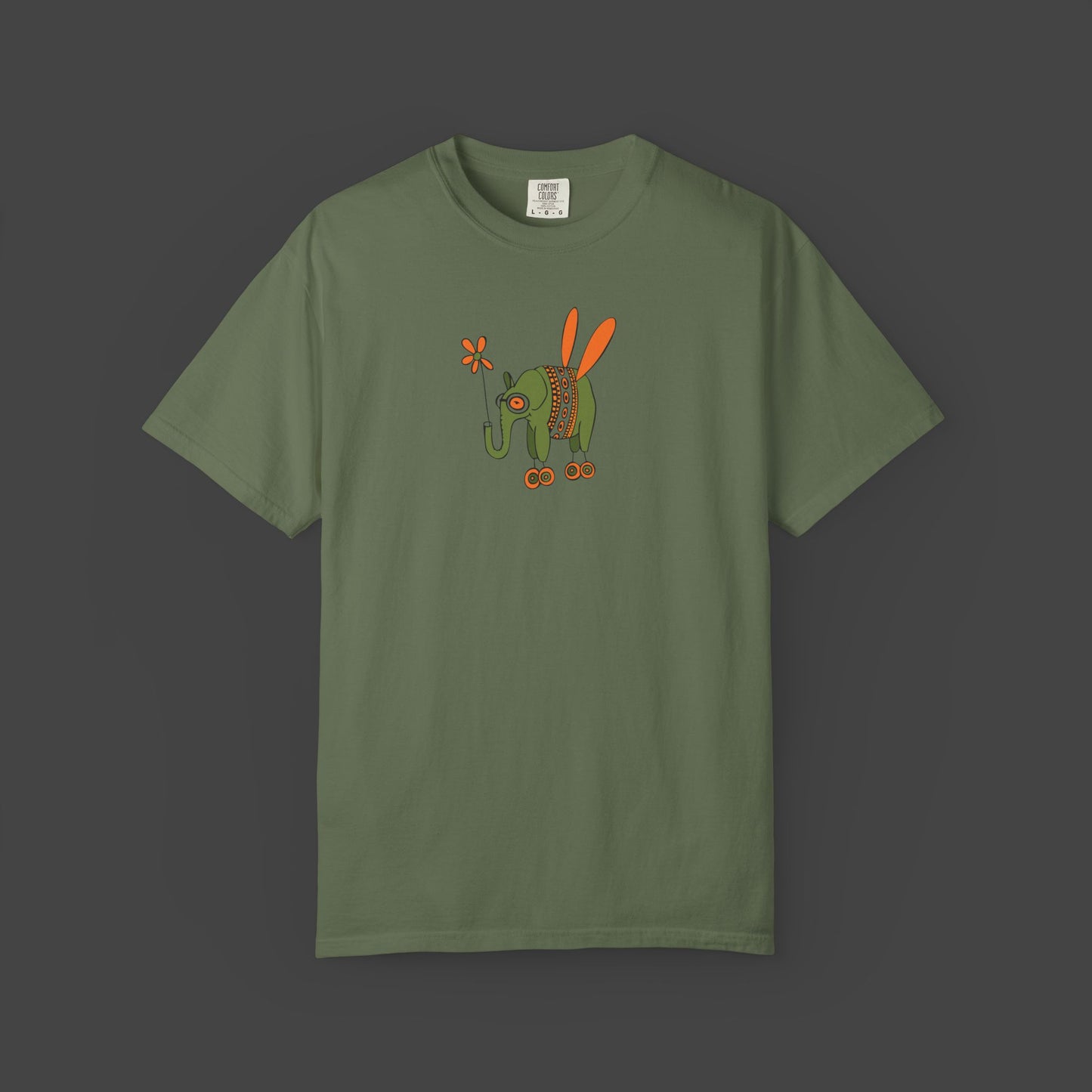 The Flying Elephant Unisex T-shirt by Printify features Jarrod Eastman’s whimsical art—a flying elephant with orange wings and a flower tail on an olive green, garment-dyed shirt. Add charm and creativity to your wardrobe with this inspirational design.