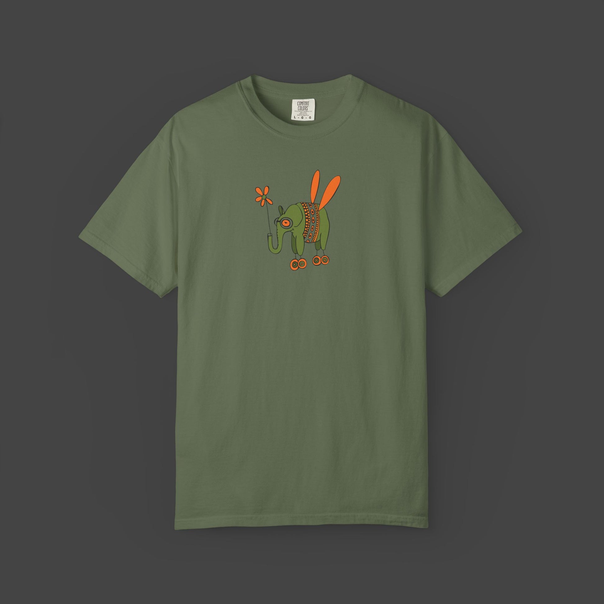 The Flying Elephant Unisex T-shirt by Printify features Jarrod Eastman’s whimsical art—a flying elephant with orange wings and a flower tail on an olive green, garment-dyed shirt. Add charm and creativity to your wardrobe with this inspirational design.