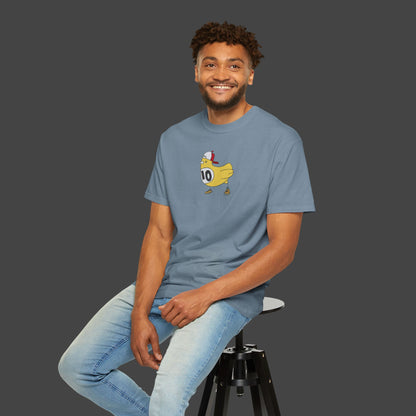 A man with curly hair and a beard wears the Chicken Scratch Unisex T-shirt by Jarrod Eastman from Printify—a blue tee with a cartoon duck and number 10—while smiling on a black stool against a plain gray background.