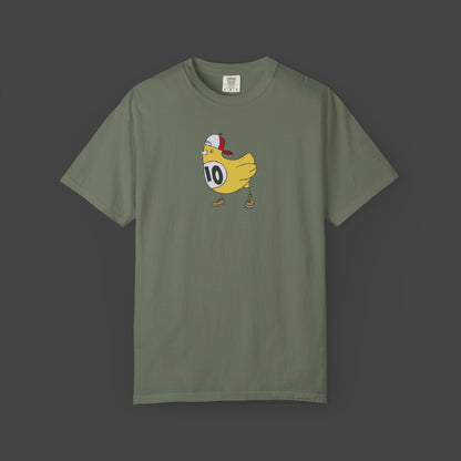 The Chicken Scratch Unisex T-shirt by Jarrod Eastman from Printify is an olive green, garment-dyed tee featuring a surreal cartoon yellow chicken in a red cap and brown shoes, wearing a white bib with the number 10 on a dark background.