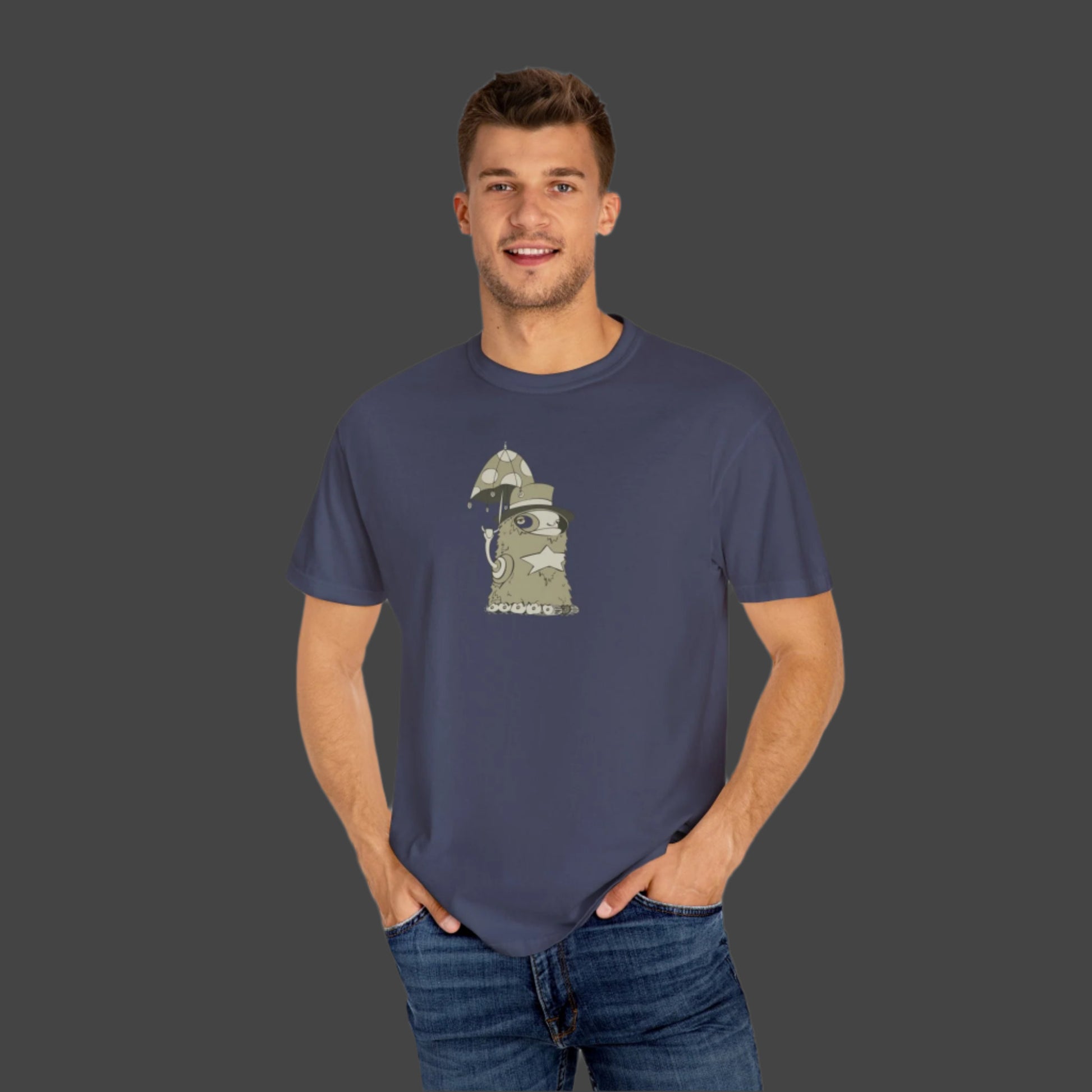 A man wears the Funky Monster T-shirt by Printify, featuring an Uptown Lester cartoon graphic of a cat as a medieval knight with sword and shield, standing with hands in pockets and smiling at the camera.