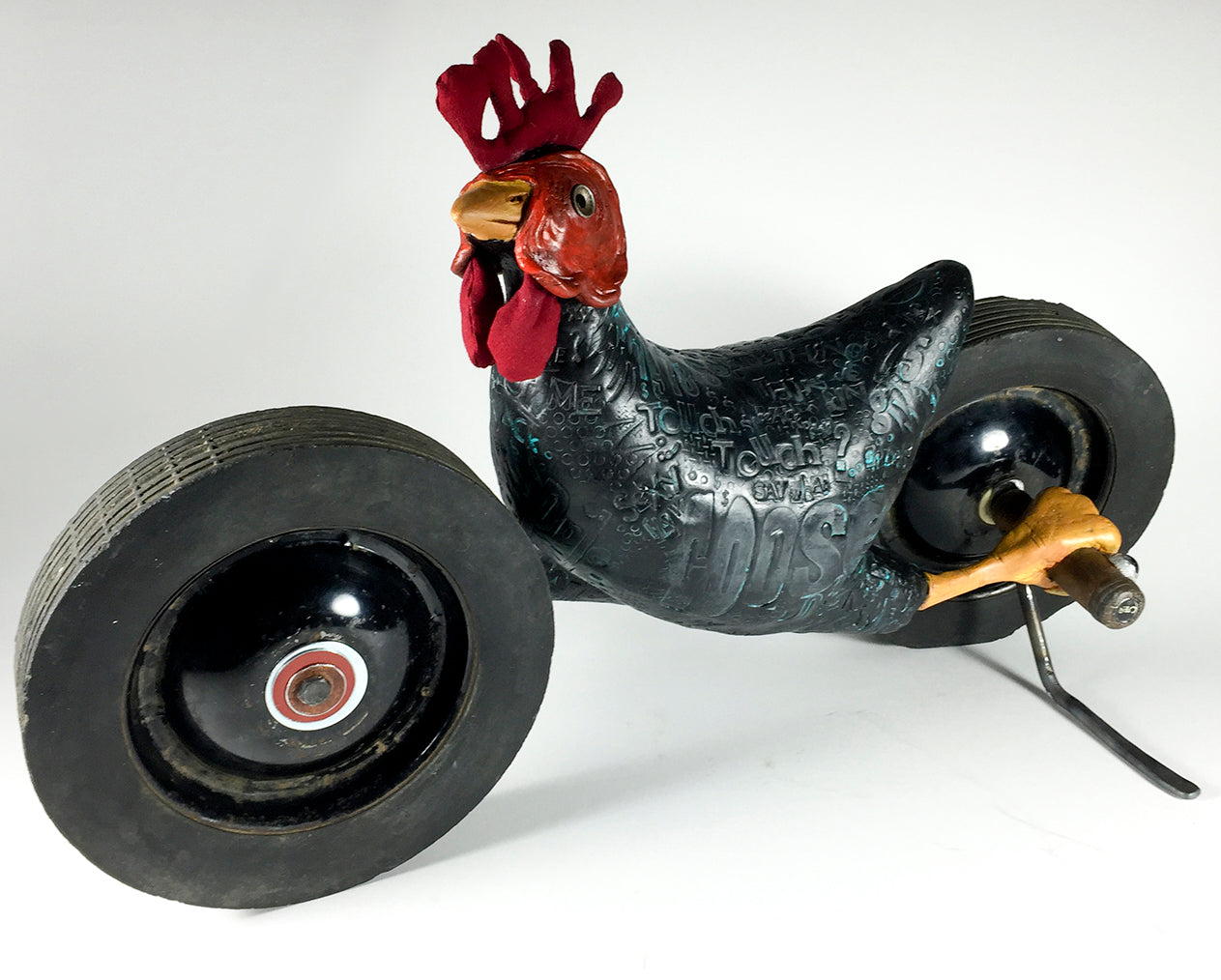 Black Chicken by jarrodeastman: A whimsical sculpture resembling a tricycle, crafted from found objects with a bright red comb, lifelike details, and large antique wheels. Displayed against a plain white background.