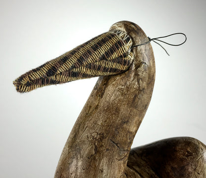 The Bob by jarrodeastman is a wooden bird sculpture featuring a long beak wrapped in patterned fabric and finished with a thin black cord, set against a plain light background.